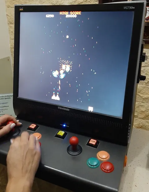 Detalle de una recreativa con Galaga: pantalla, joystick y botones.